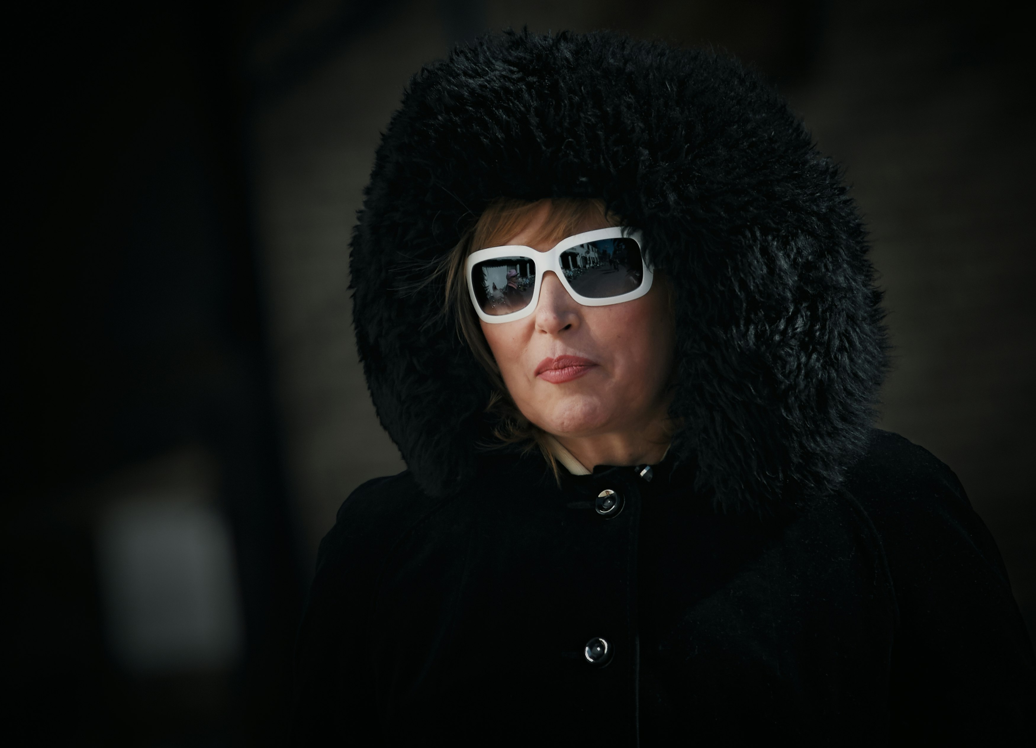 woman in black fur coat wearing black sunglasses